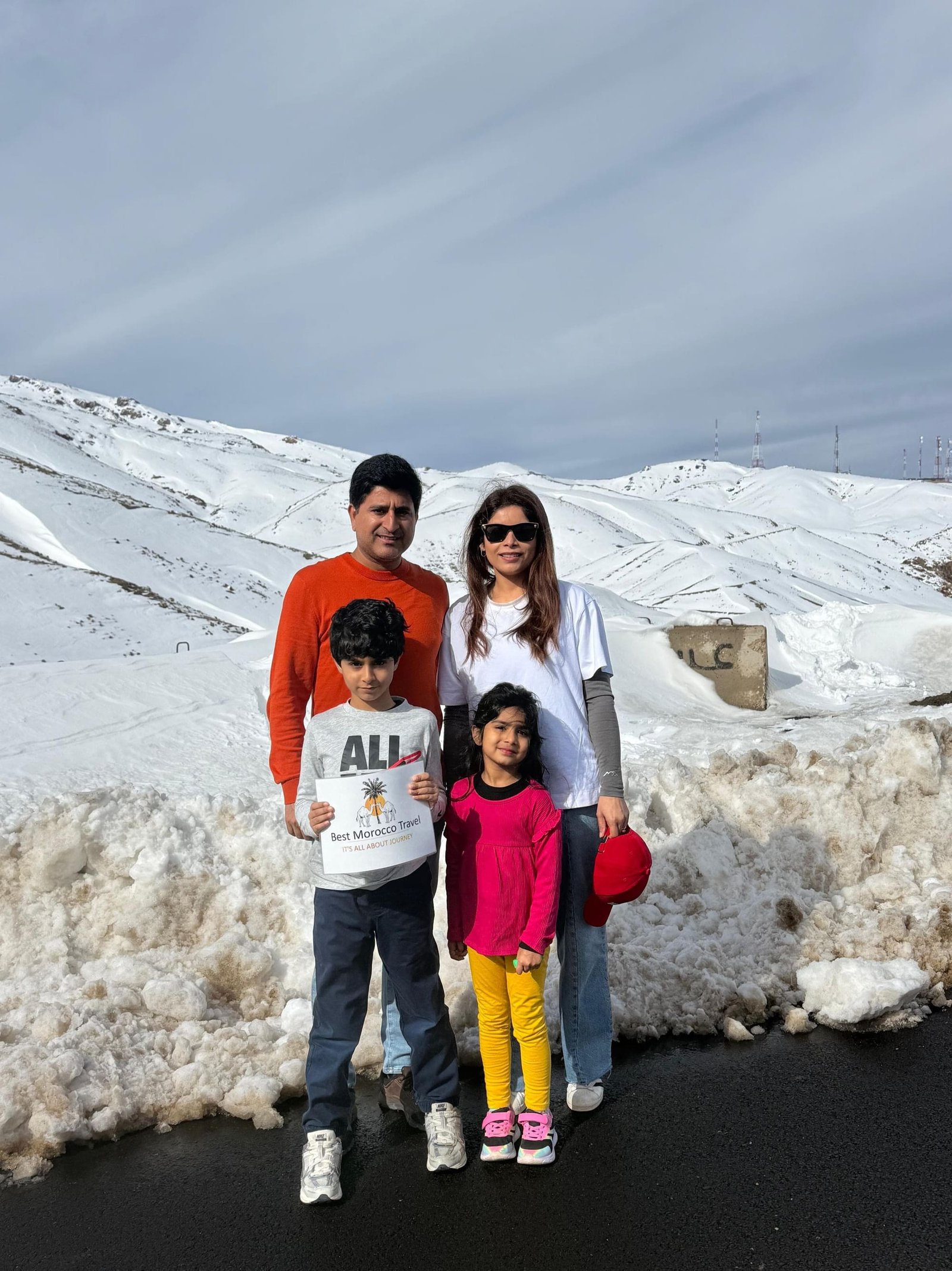 A family standing in fresh snow on a High Atlas pass during a December tour of Morocco